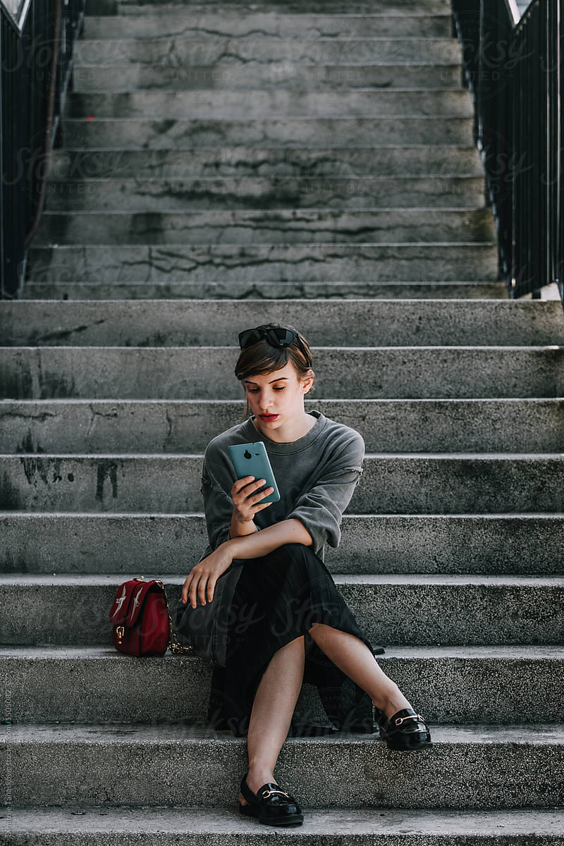 Young woman with mobile phone sitting on the stairs.