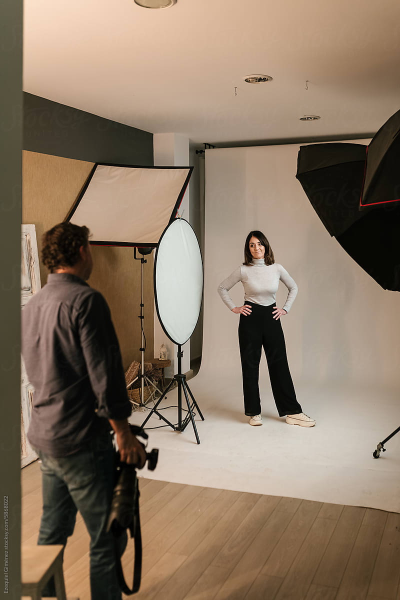 Photographer looking at woman posing in photo studio