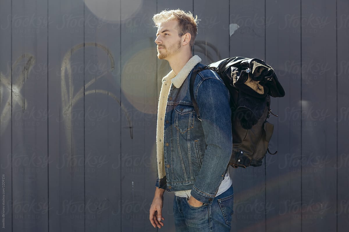 Portrait of Man in Denim Jeans and Shearling Lined Jacket Carrying Leather Backpack