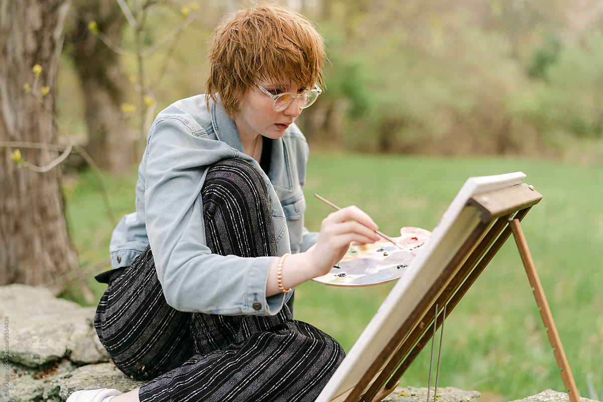 young artist painting on canvas outdoors