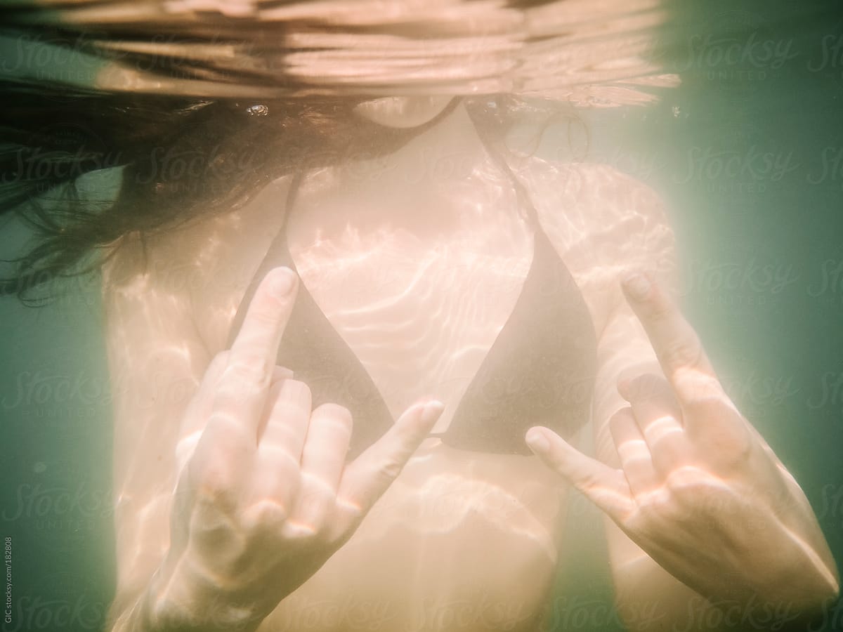 Young woman showing rock and roll gesture underwater