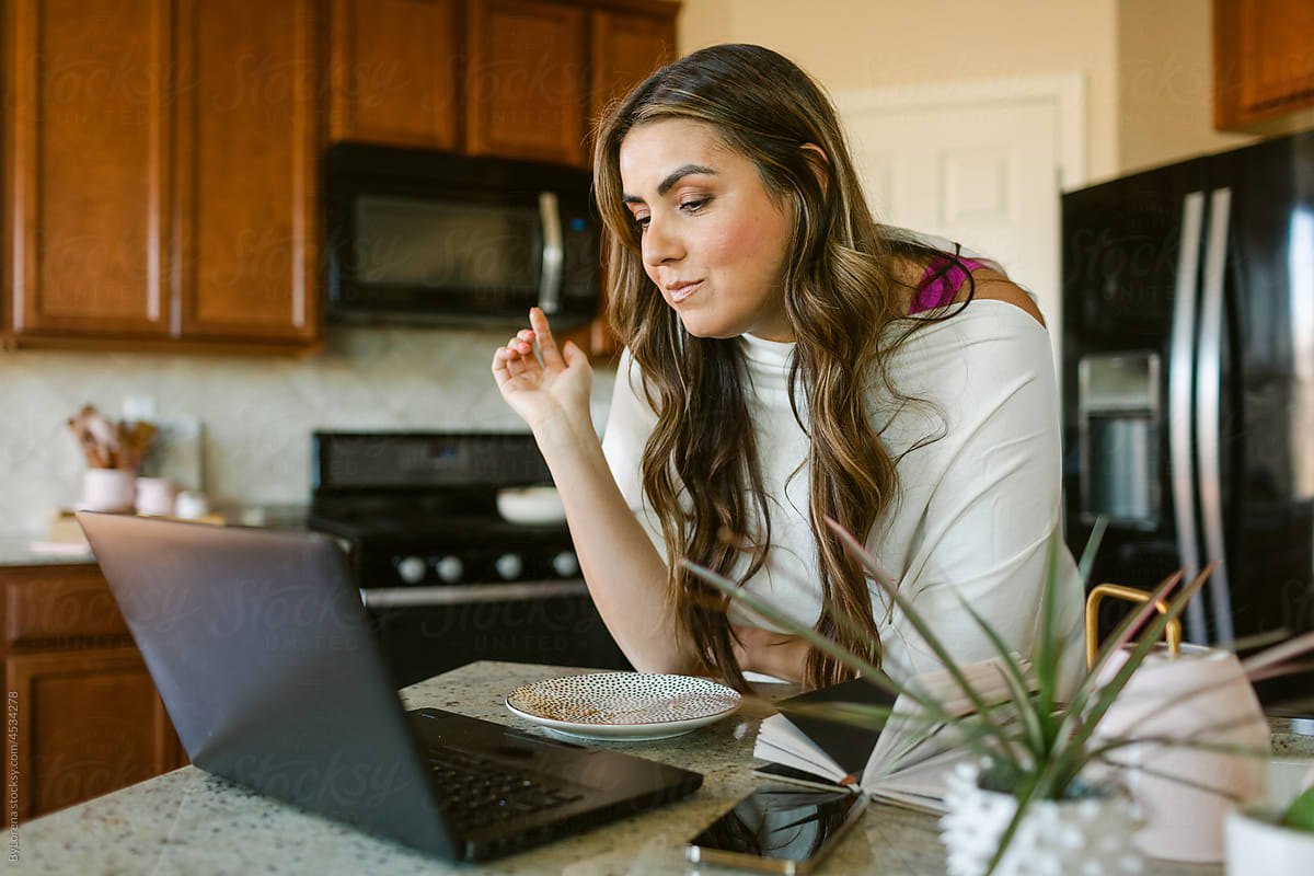 Woman in kitchen with laptop during breakfast time