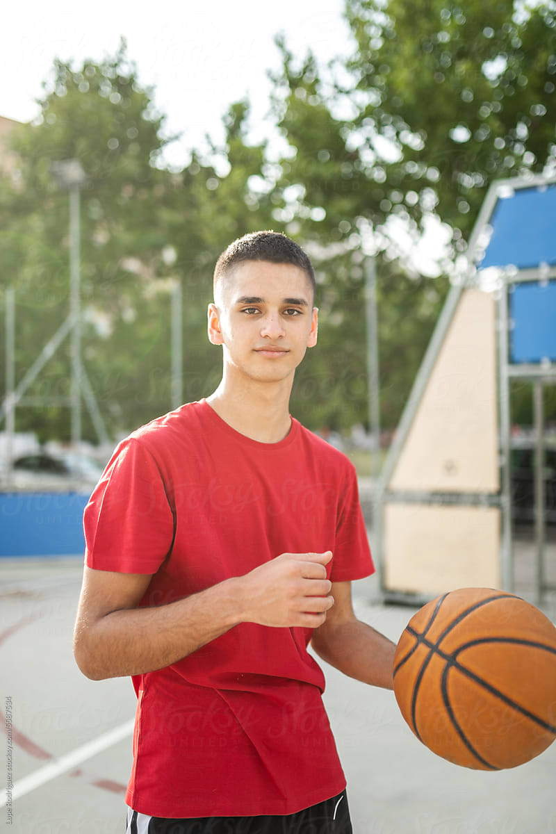 portrait of teenager playing basketball in a city
