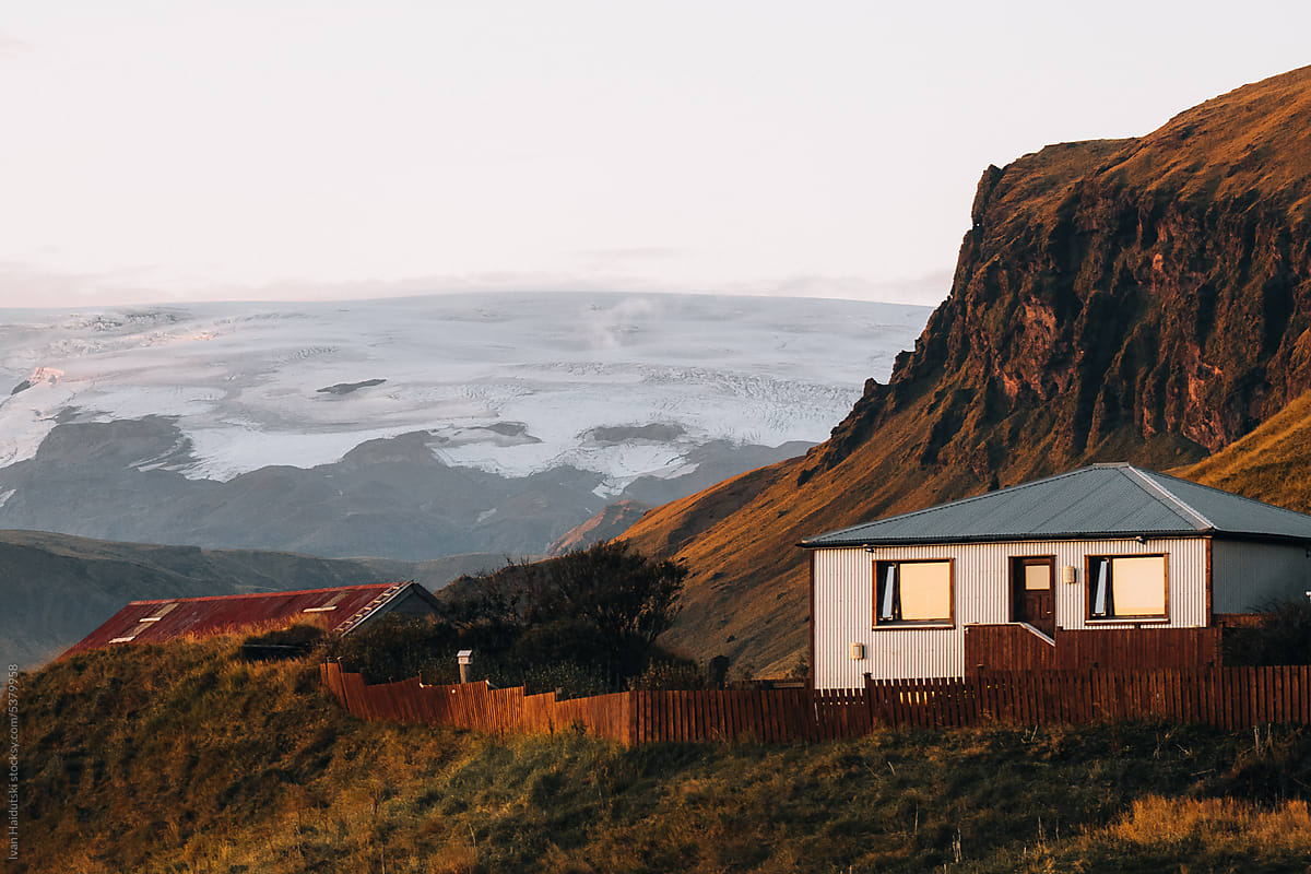 Wooden Houses with glacier backdrop at sunset in Iceland