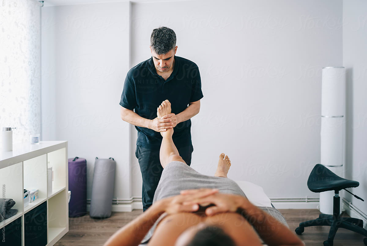 Chiropractor massaging feet of client in medical clinic