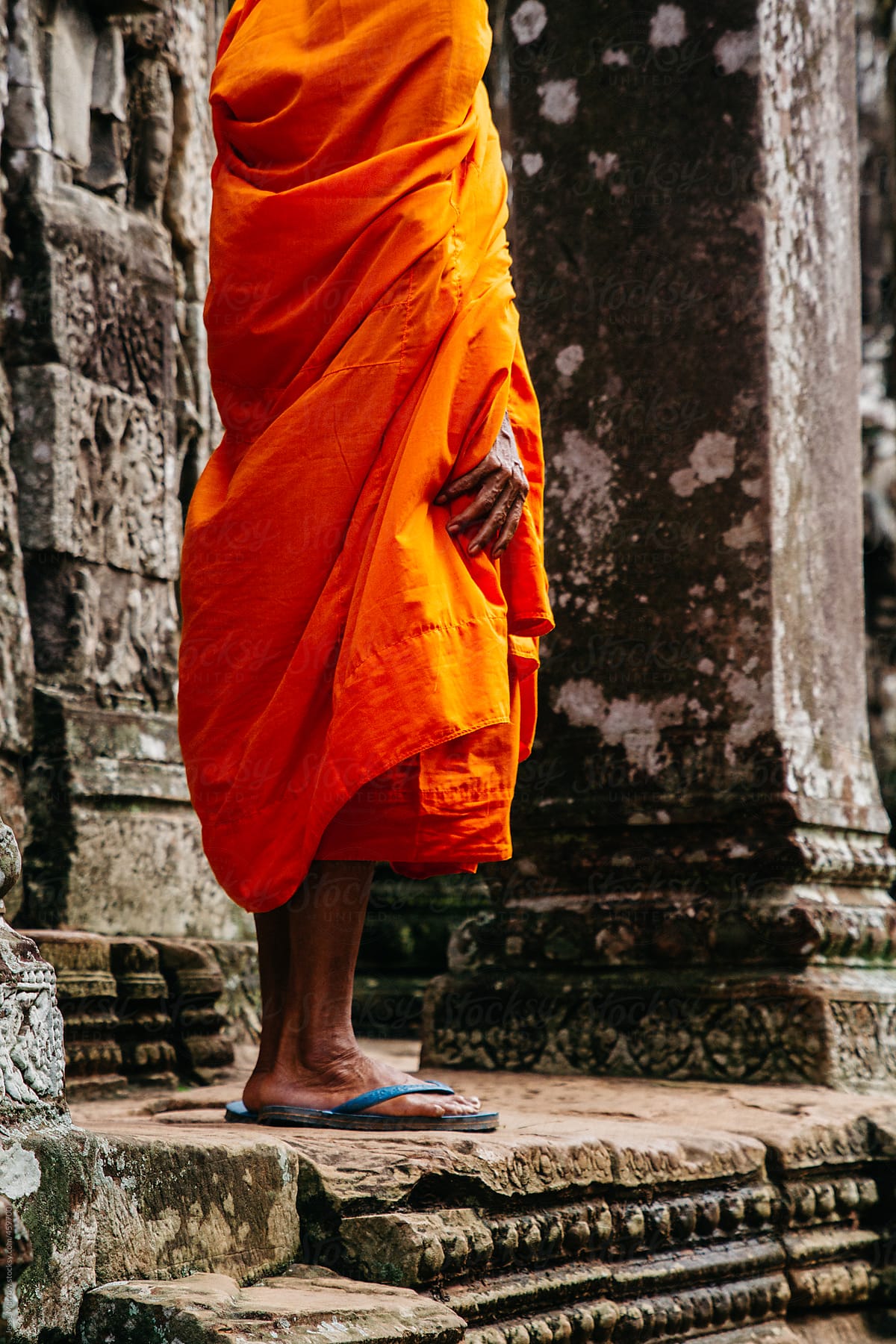 Monk stands in front of temple holding robe