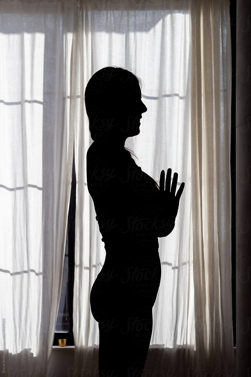Woman meditating in Tadasana pose against window