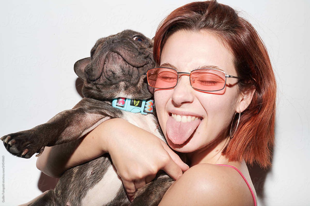woman showing tongue embracing dog