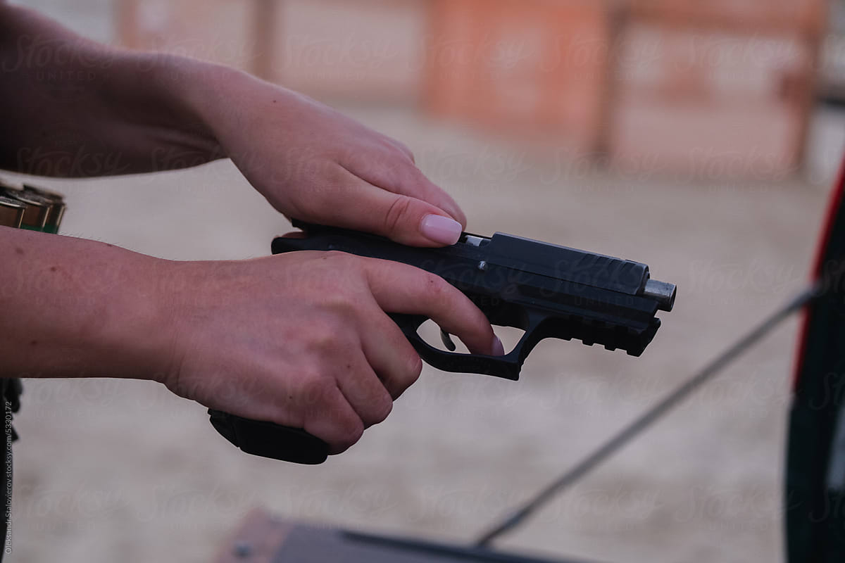 Close up shoot female hands  loads a pistol.