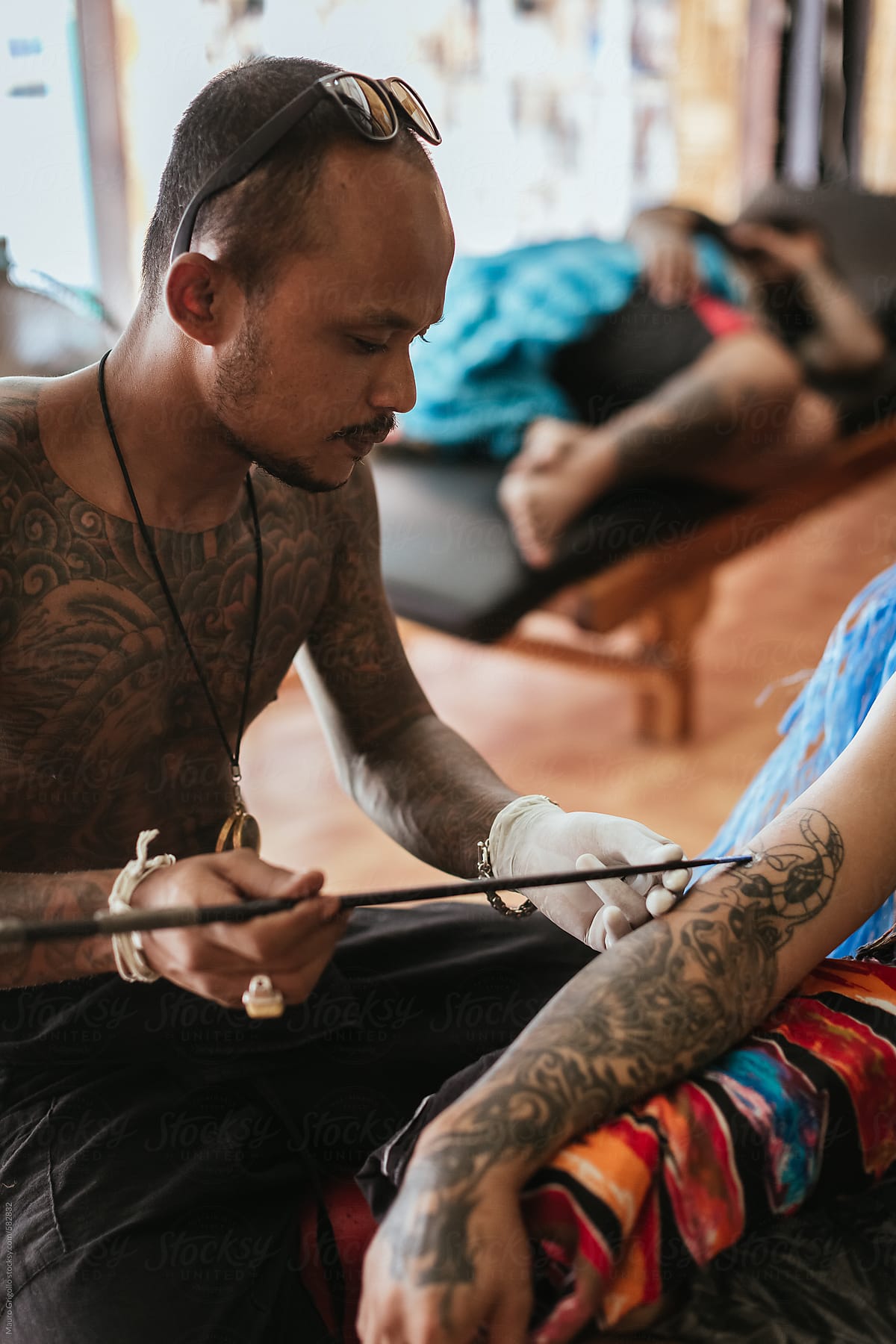 Thai Tattoo Artist Working On A Tattoo Inside His Studio
