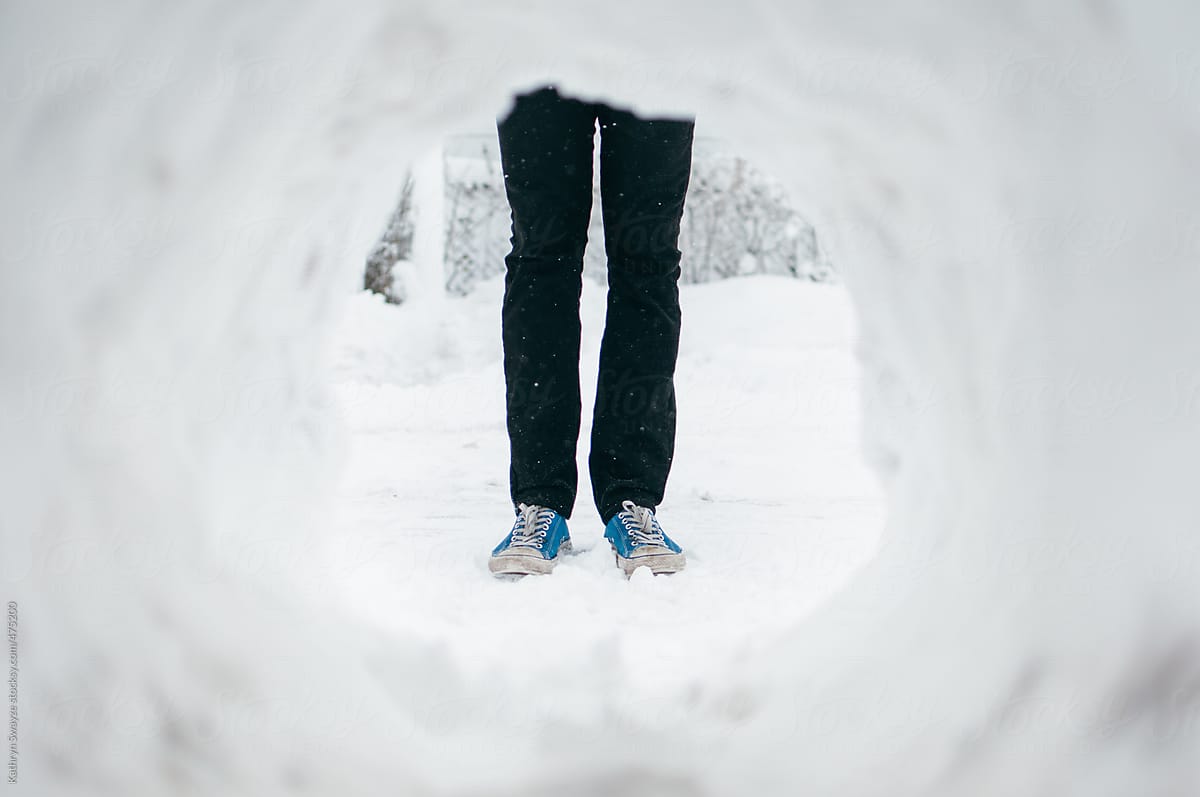 A man\'s legs seen through a snow tunnel