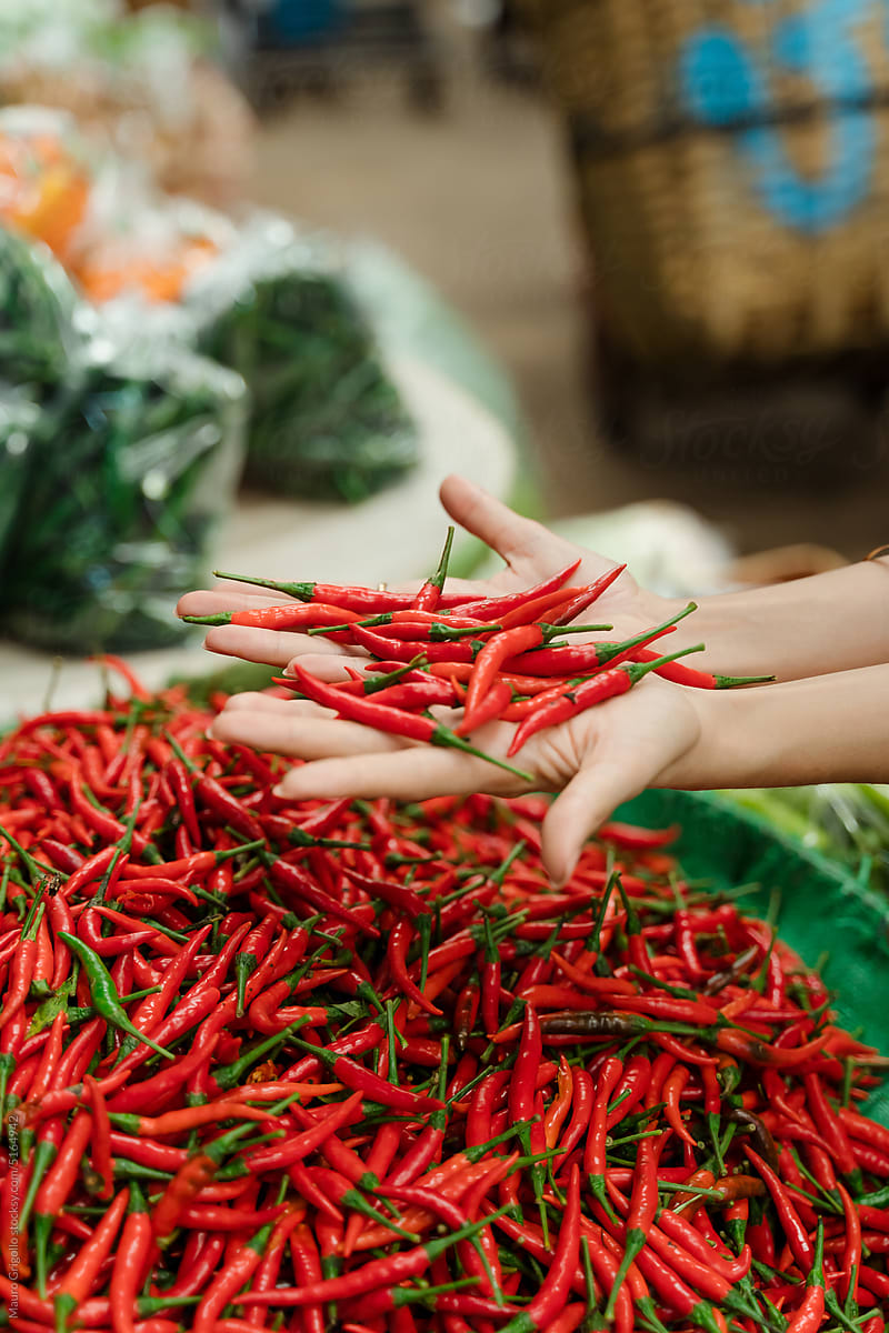 Anonymous woman looking at chili peppers at the market