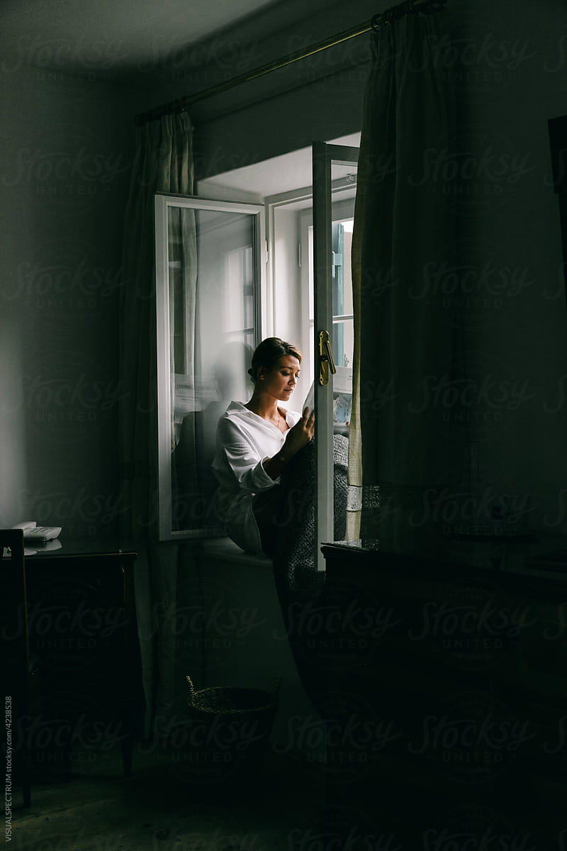 Woman Reading Newspaper in Window