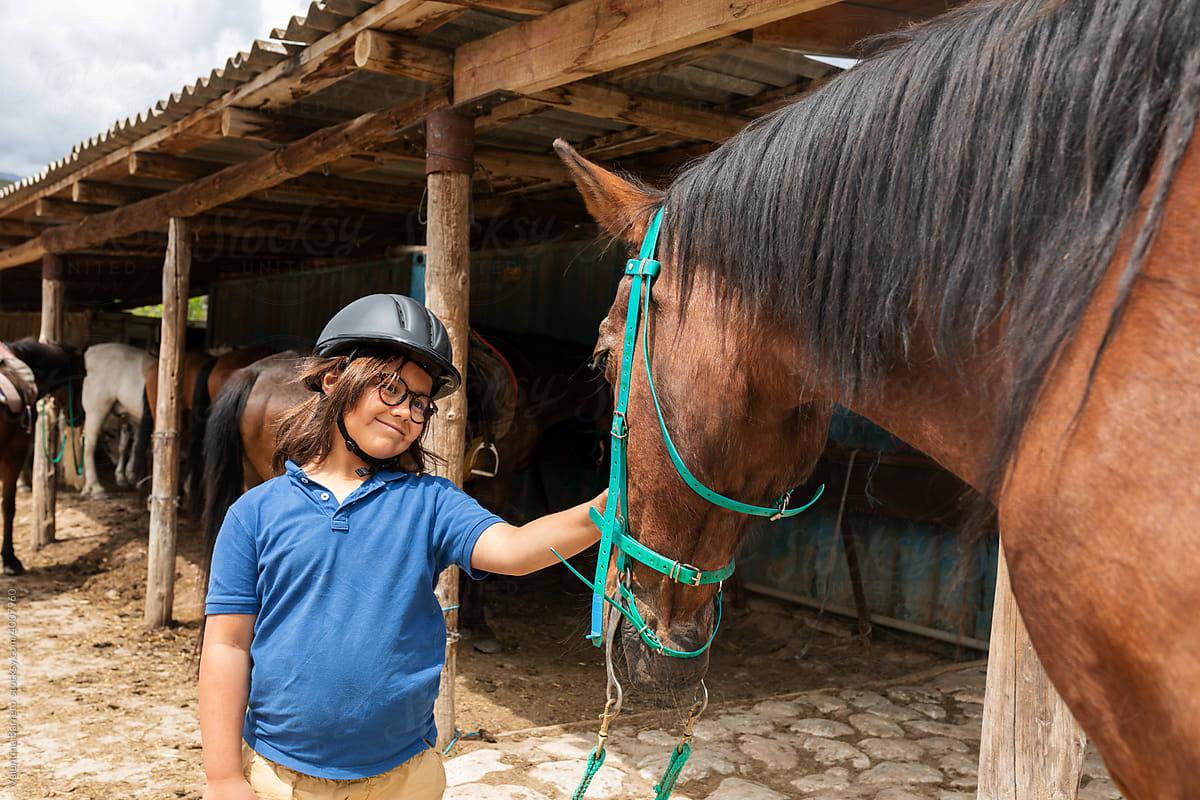 Child caressing his horse at stable