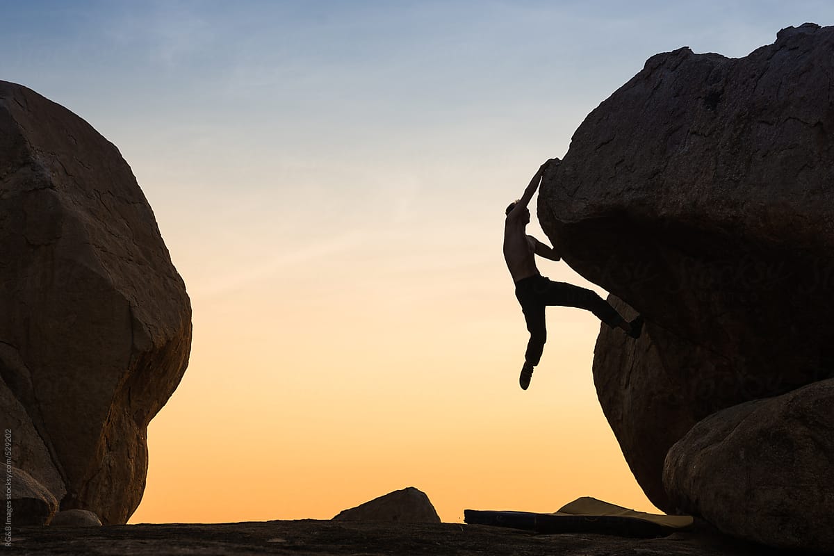 Man silhouette climbing on a big boulder