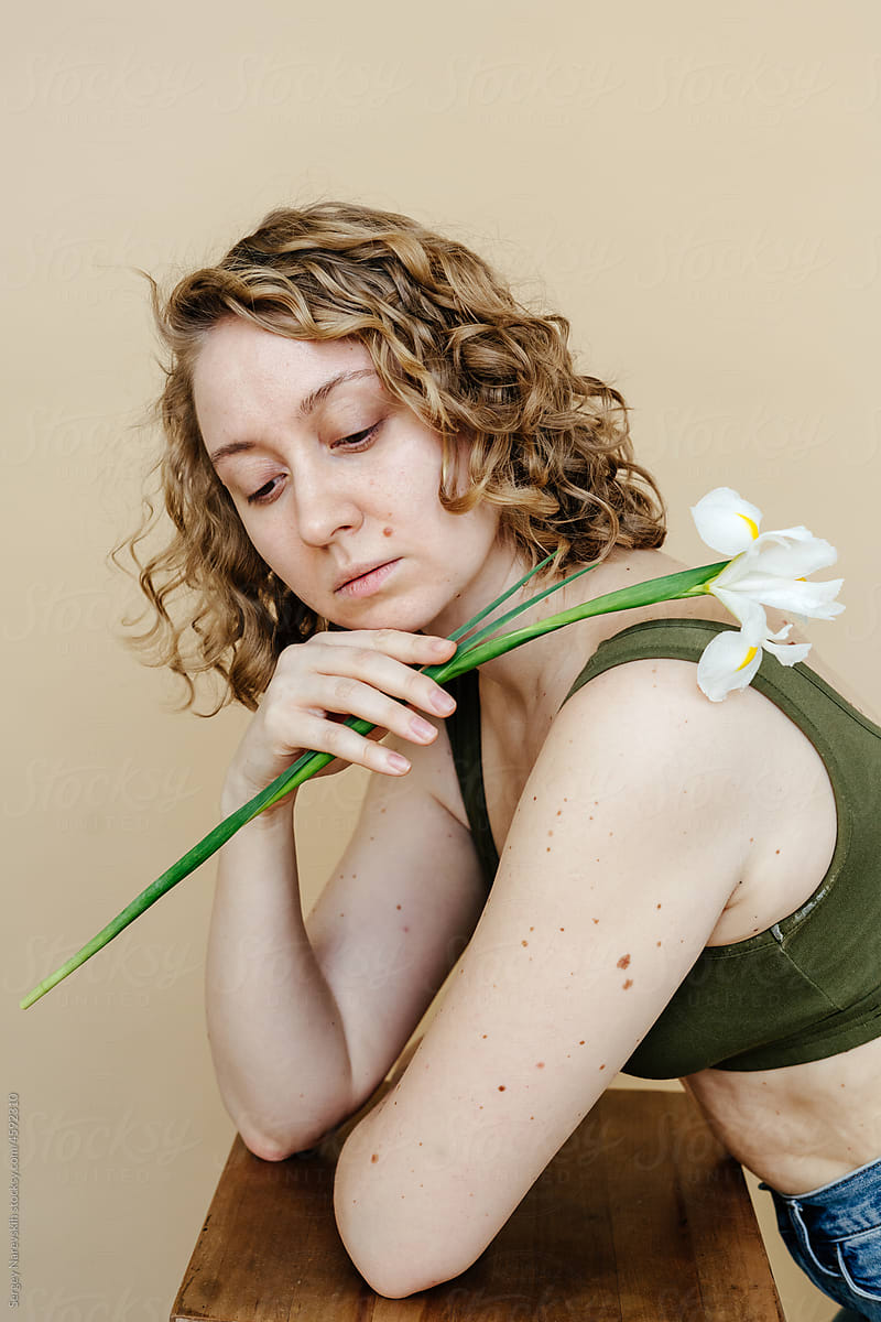 Blond female with flower leaning on chair