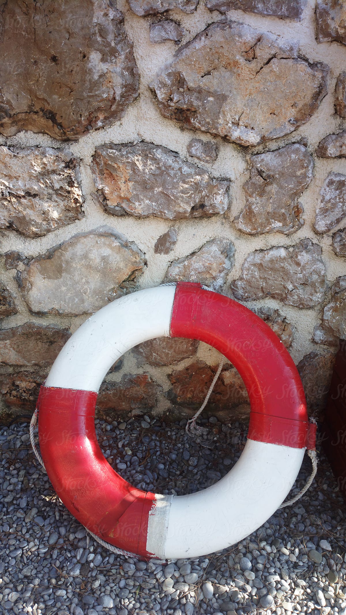 red and white sea safety belt and rocky wall