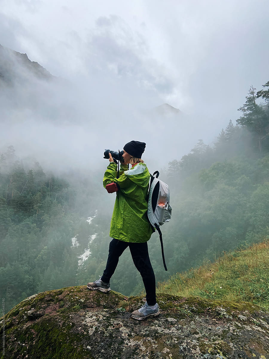 Unrecognizable hiker taking photo of waterfall