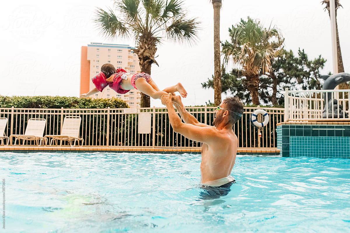 Dad and daughter playing games in the pool.