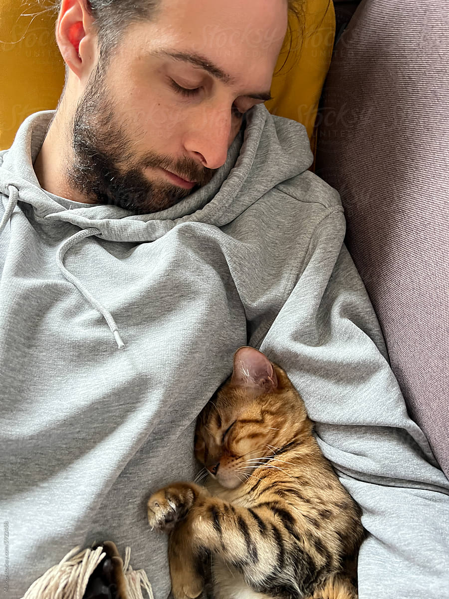 Man and cat sleeping together resting during day