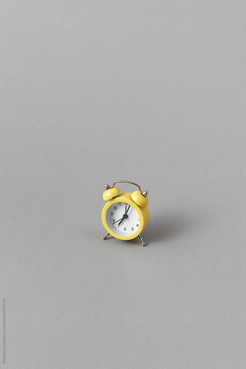 Yellow vintage alarm clock on gray background