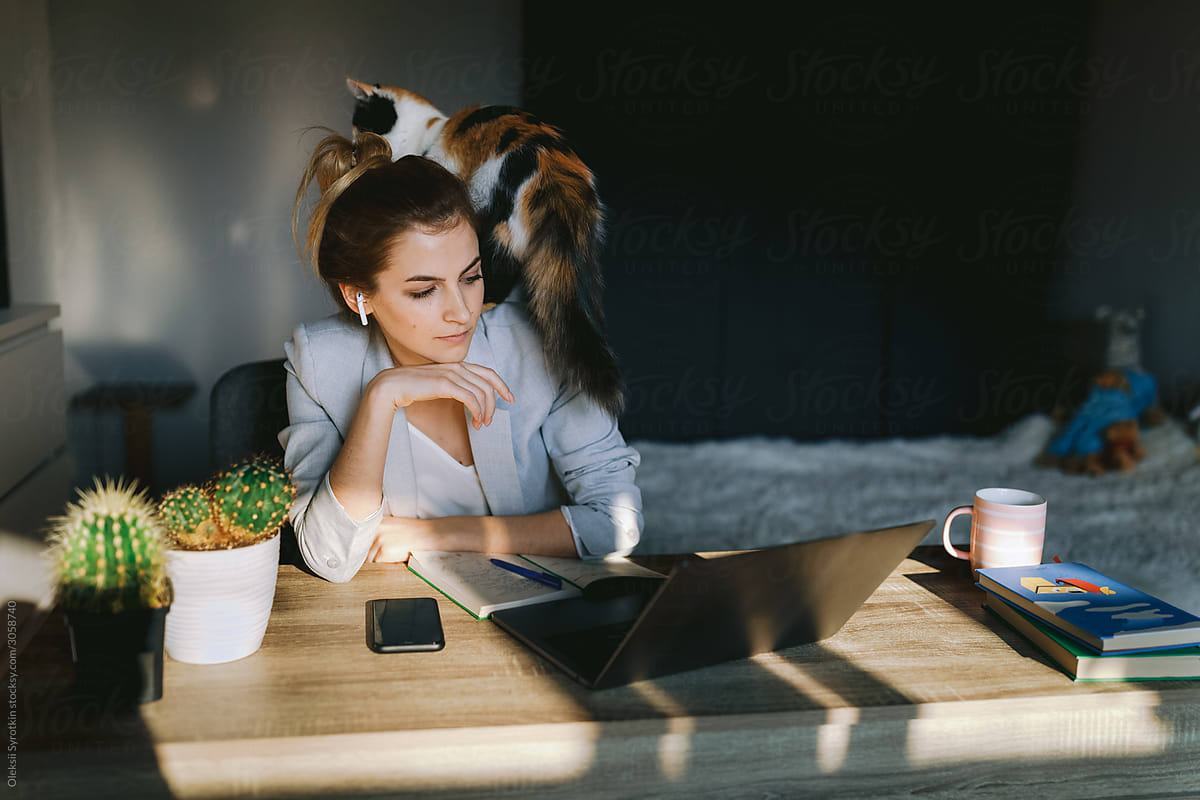 Girl working at home with her cat.
