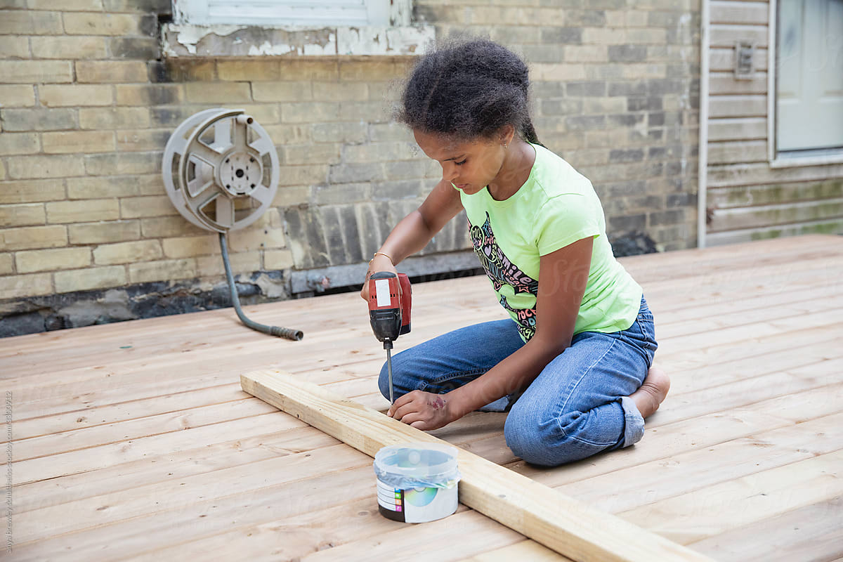 Tween girl  using power tools to help build a deck