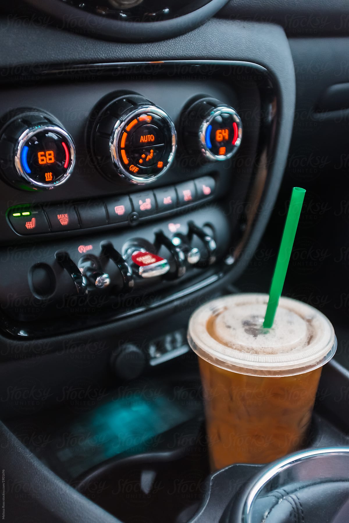 An iced coffee drink placed in a cup holder inside a car.