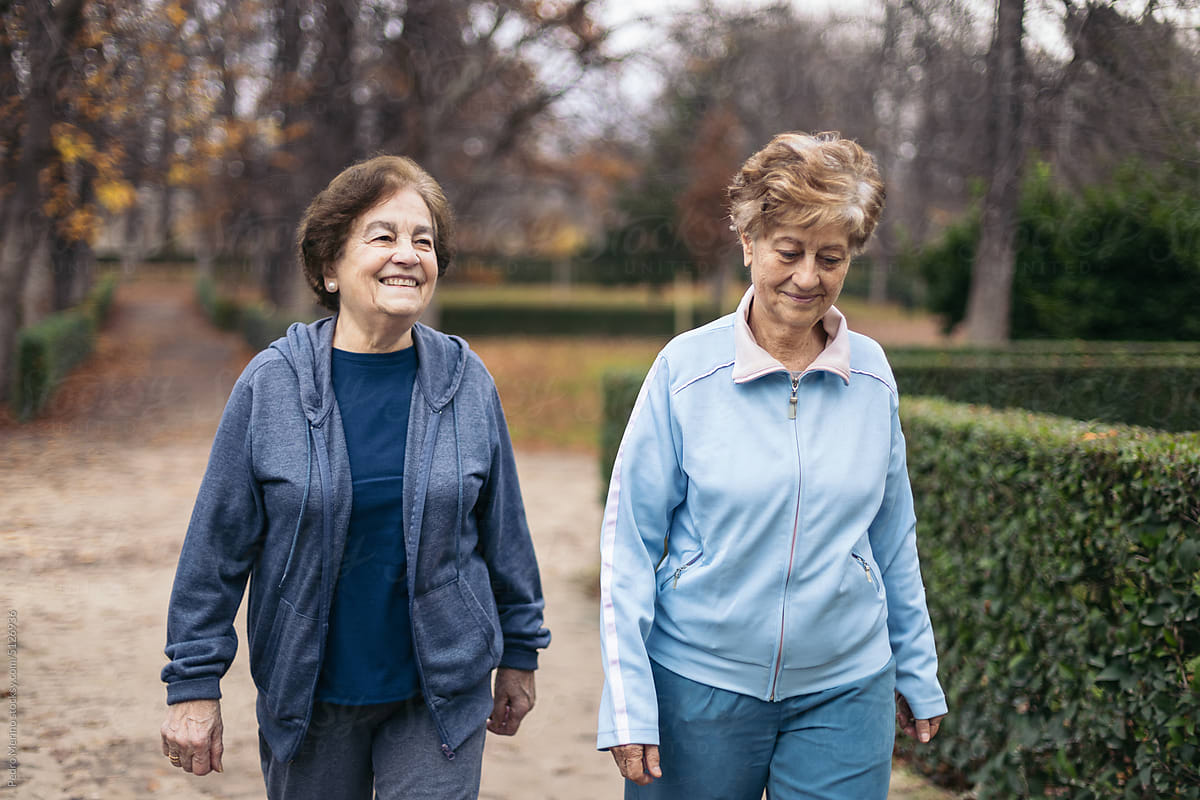 Two elderly women in sportswear walking in the park