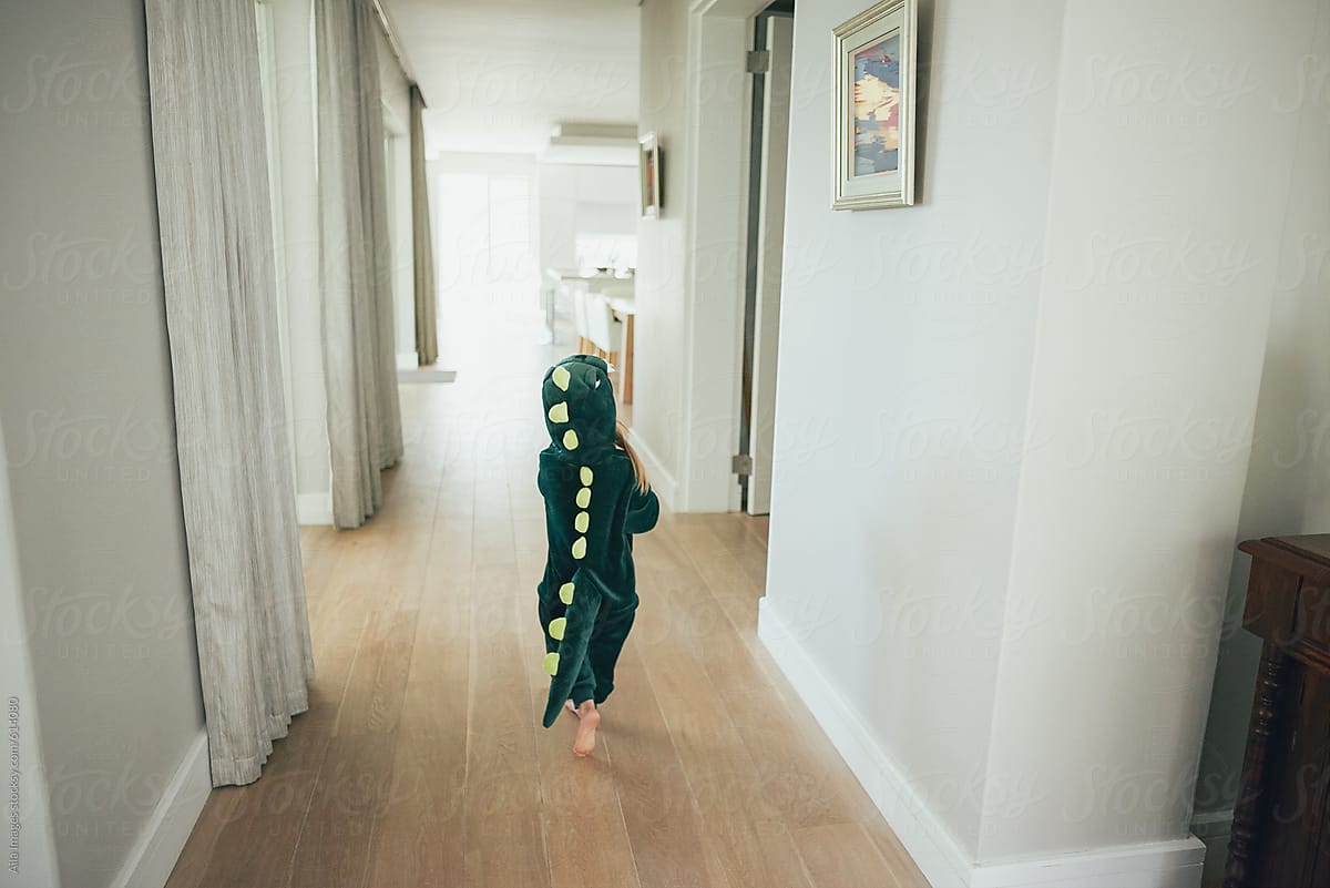 Cute little girl wandering around in dinosaur costume in family home