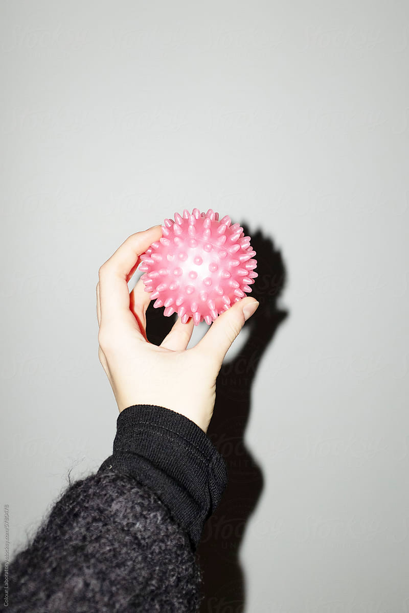 Hand holding a neon pink sport spike ball with hard direct flashlight