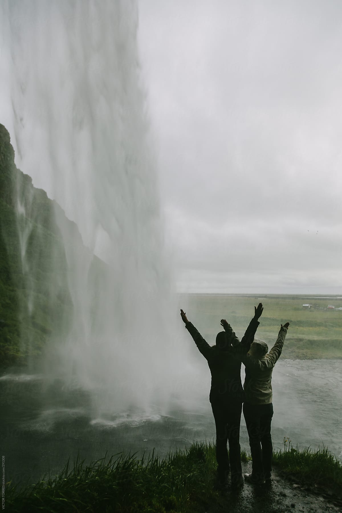 Persons inside the Seljalandsfoss Waterfall, Iceland