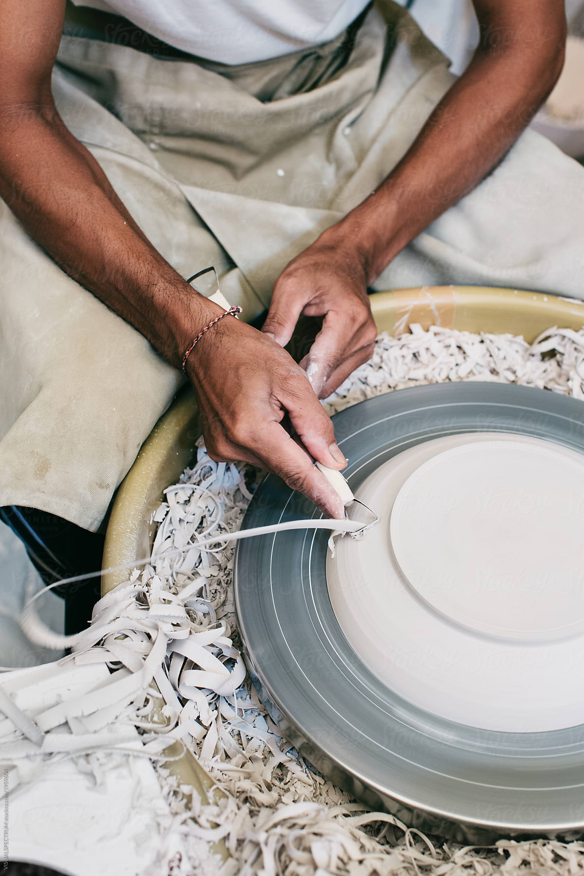 Closeup of Artisan Master Potter Shaping Plate on Flywheel in Bright Art Studio