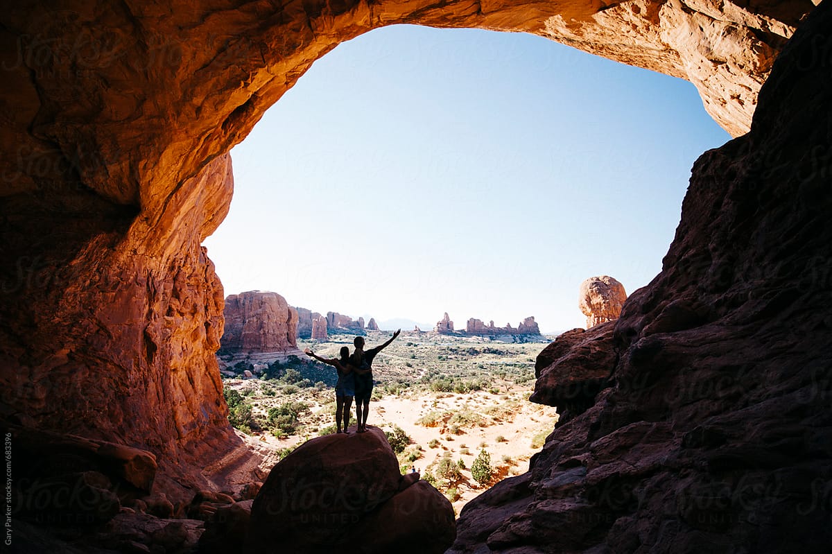 Two people under a large rock arch