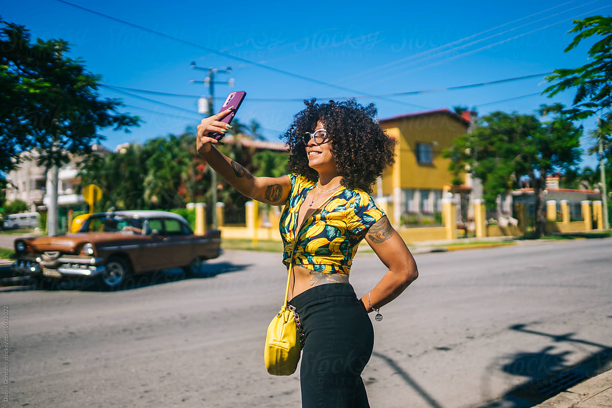 A stylish African American woman takes a selfie on the street