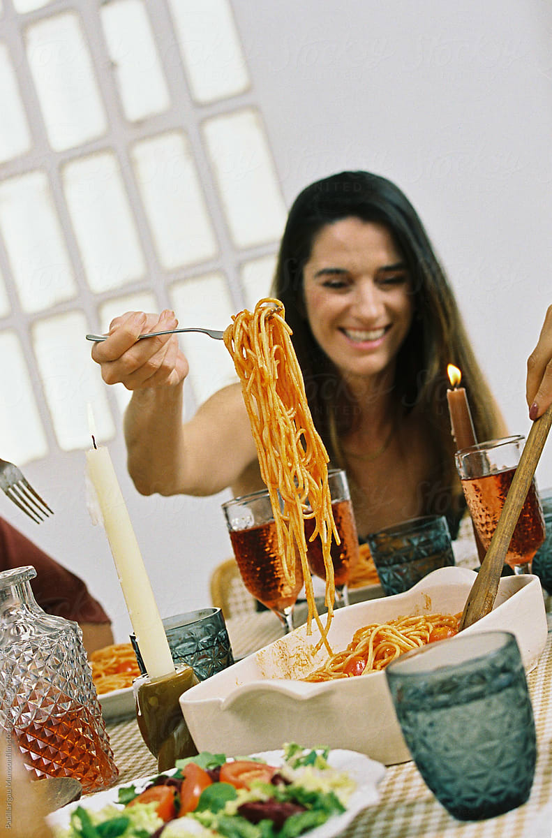 Girl laughing while eating spaghetti