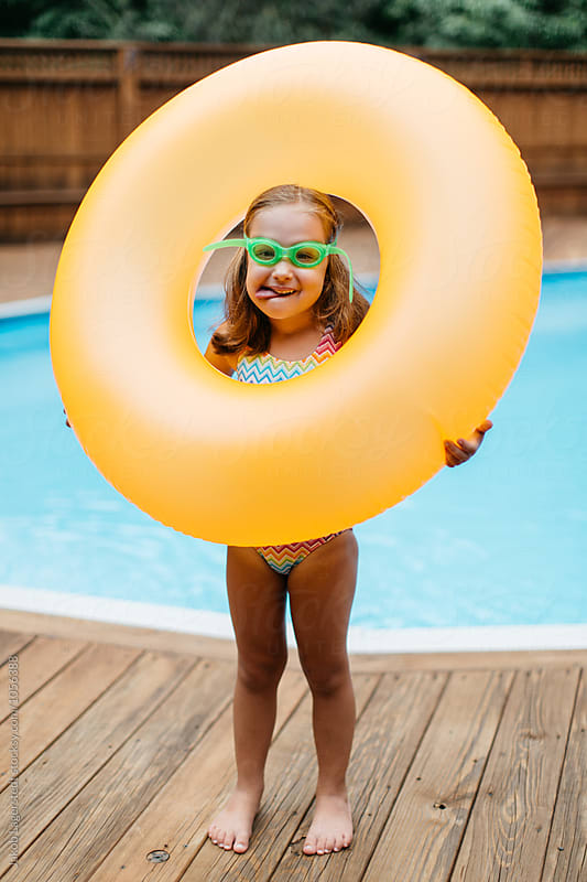 Cute young girl playing with her inner tube by a pool