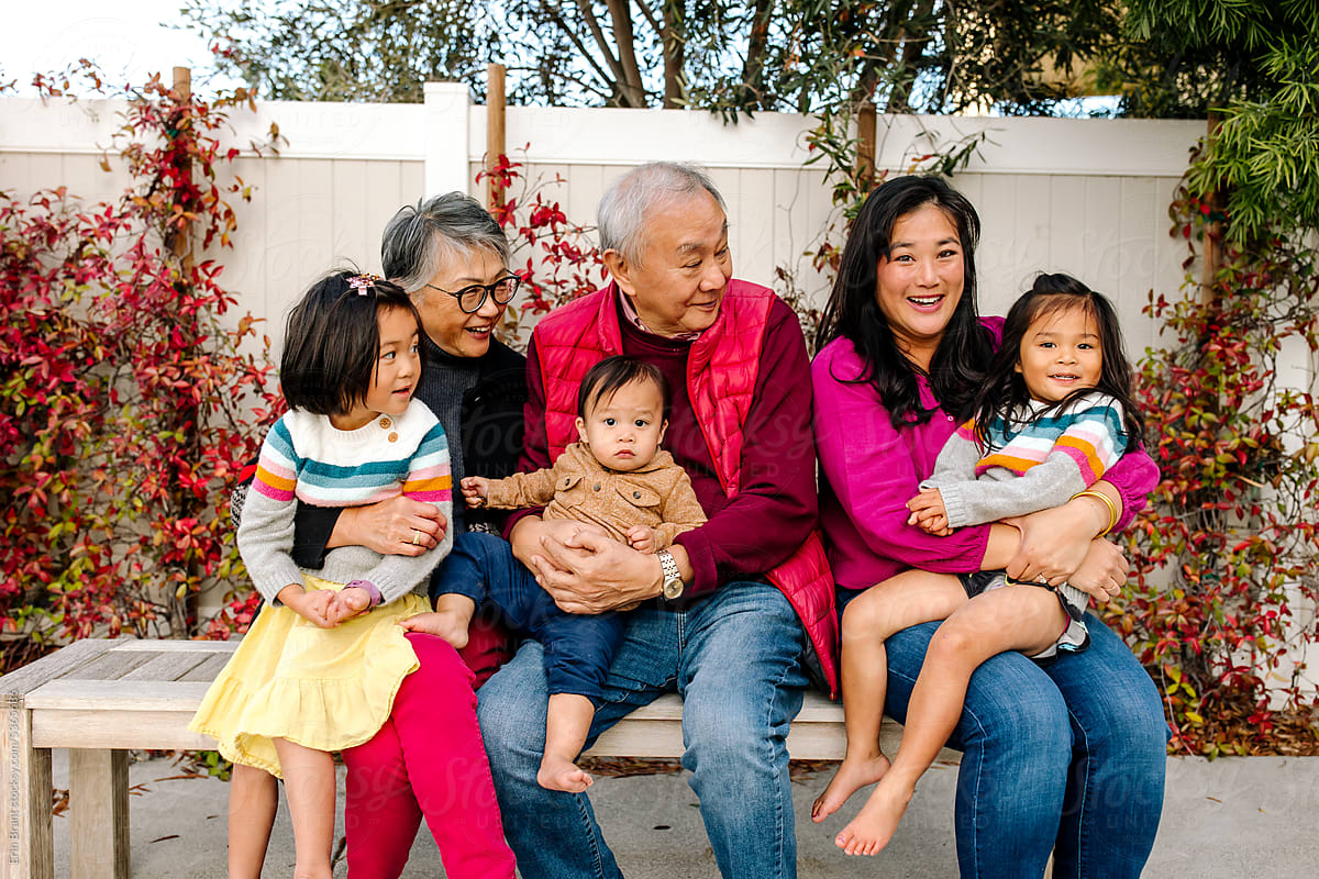 Smiling asian family with grandparents sitting outdoors together
