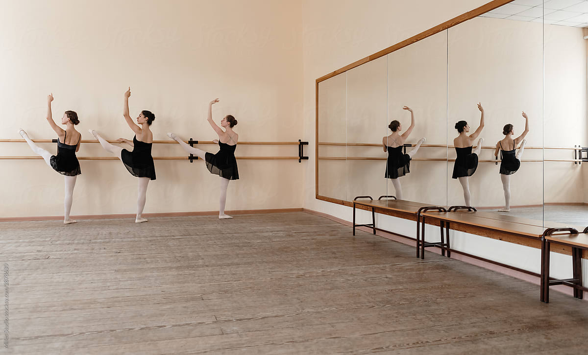 Ballerinas stretching legs near mirror