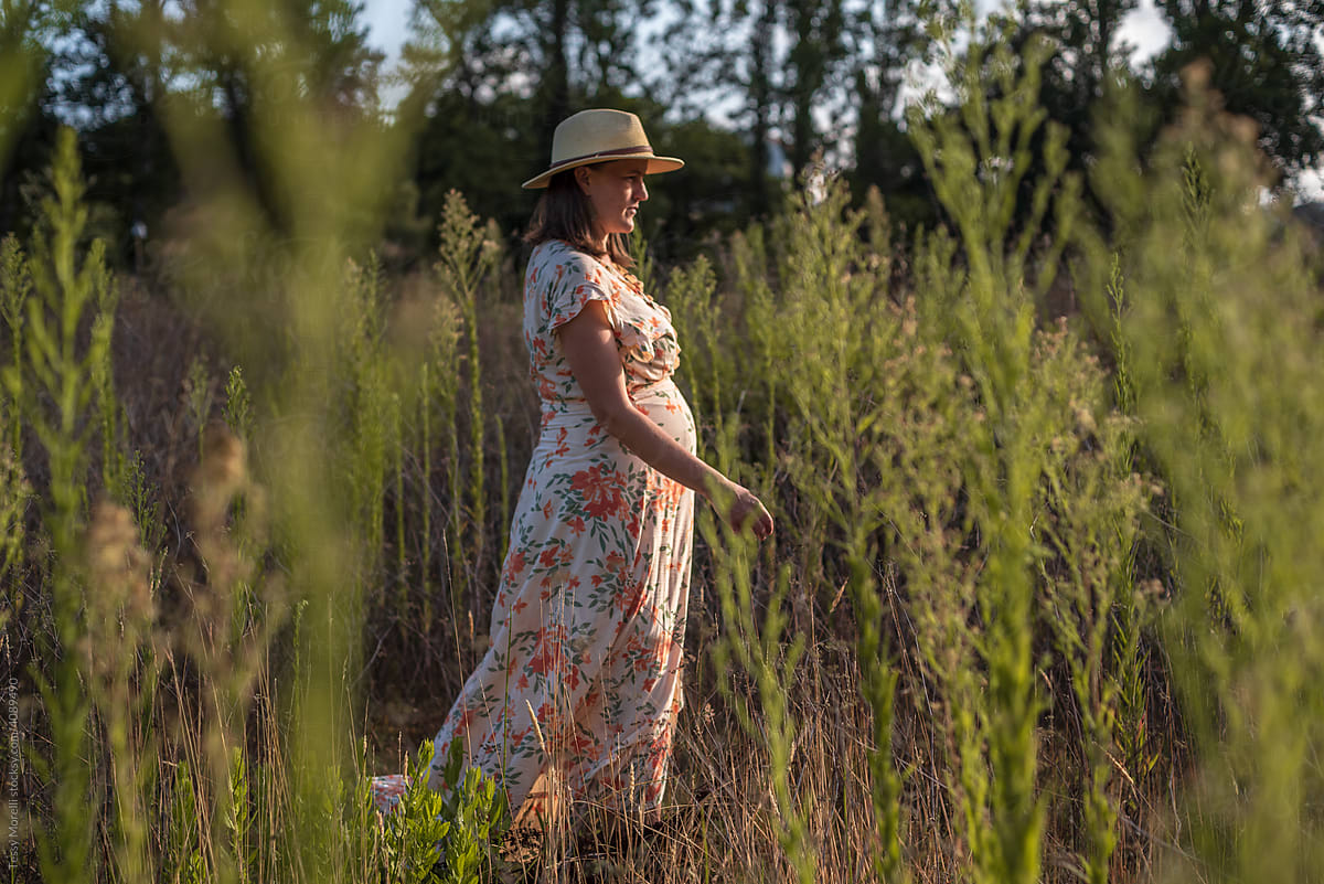 Candid portrait of mum to be walking in the field
