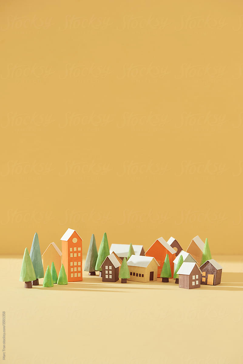 Miniature houses with fir trees on yellow background