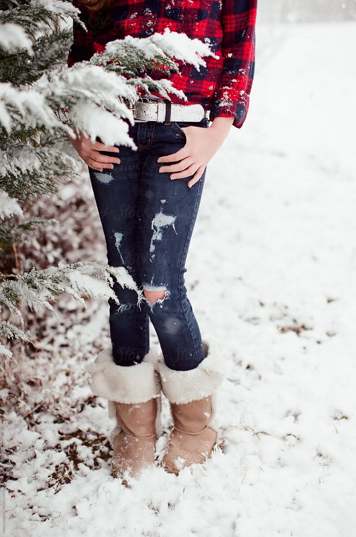 Girl in red and blue flannel shirt dancing and playing in the falling snow.