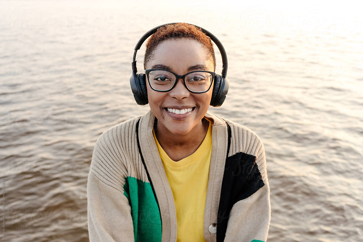 Portrait of young woman in headphones against sea water
