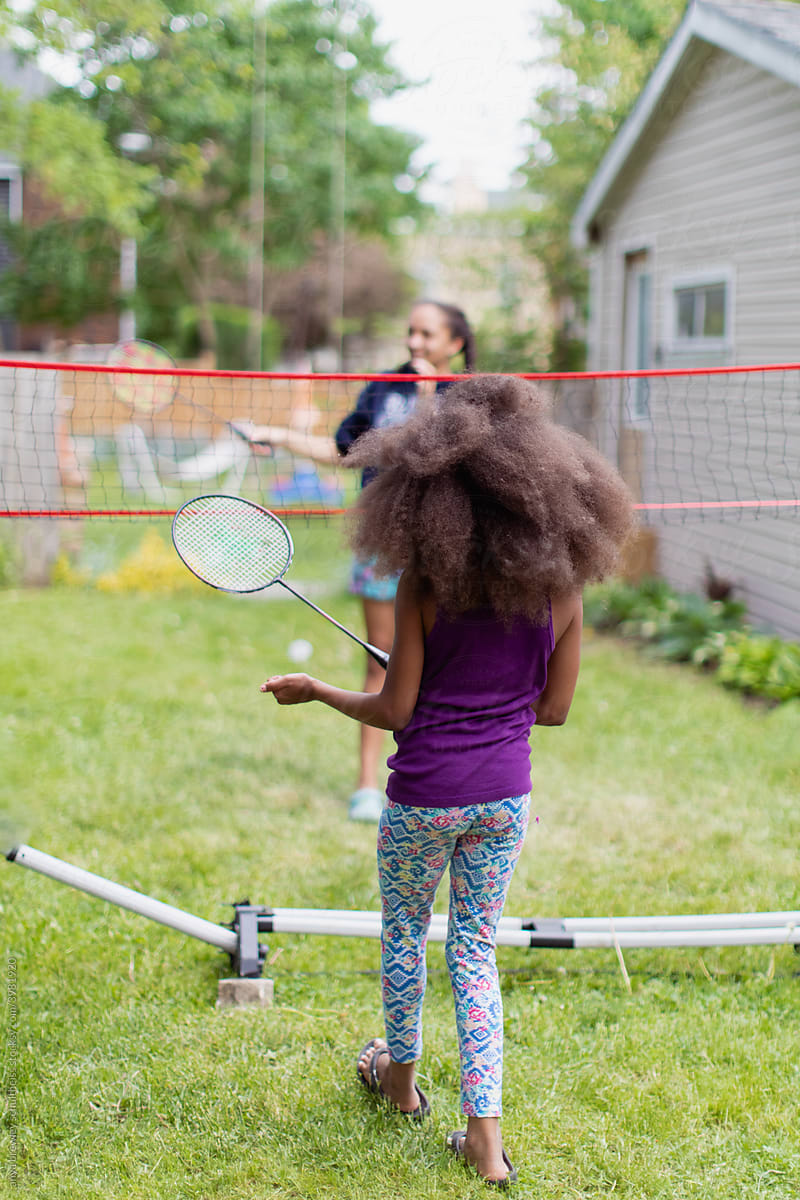 Two girls playing badminton in their backyard