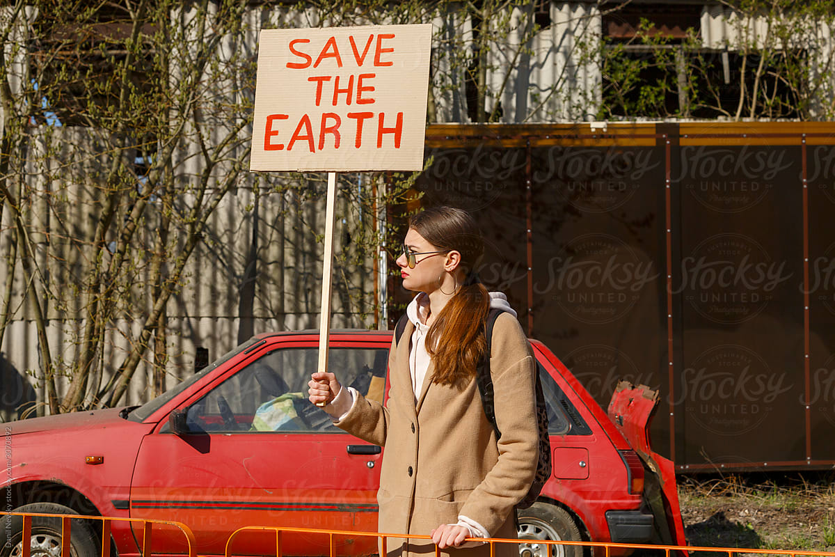 Young woman with ecological banner near car