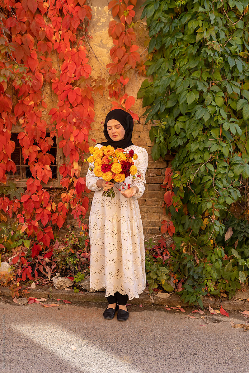 muslim woman holding autumn bouquet of flowers