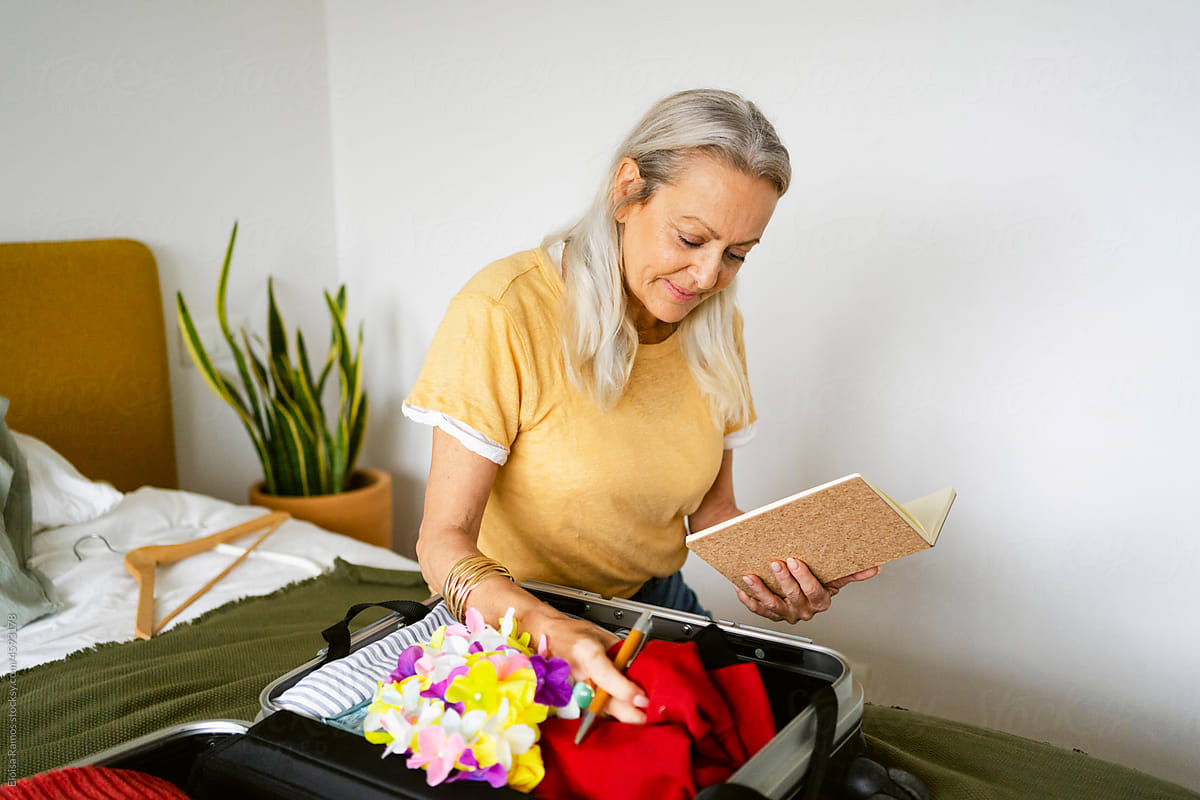 Beautiful gray hair woman preparing suitcase