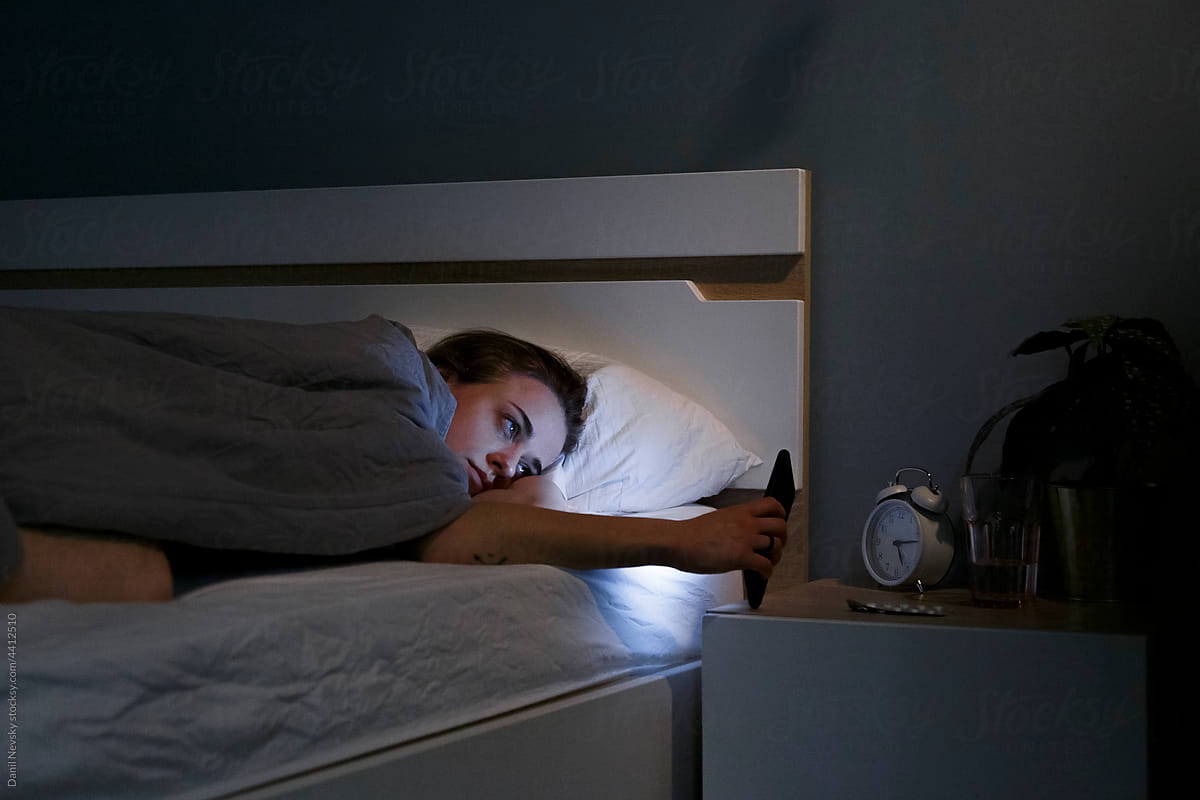 Woman having insomnia using smartphone in bed