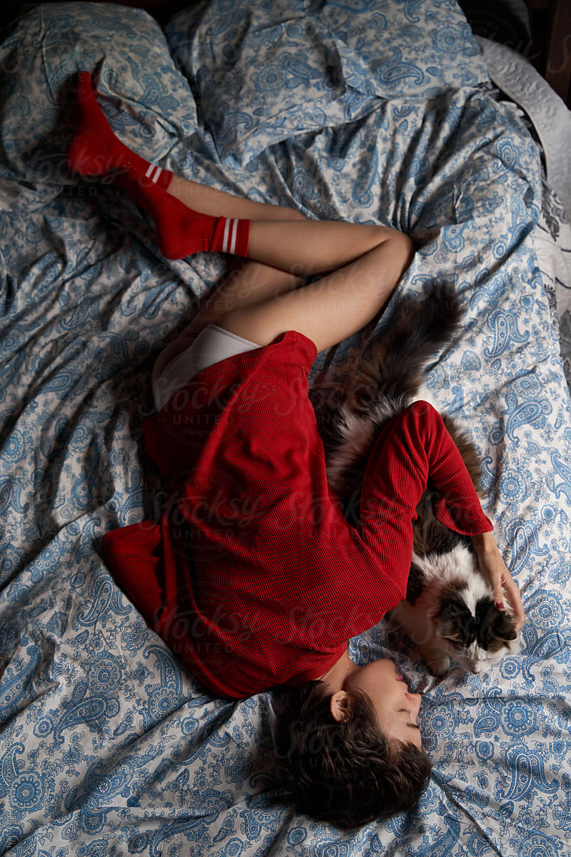 Young woman hugging cat and sleeping on bed