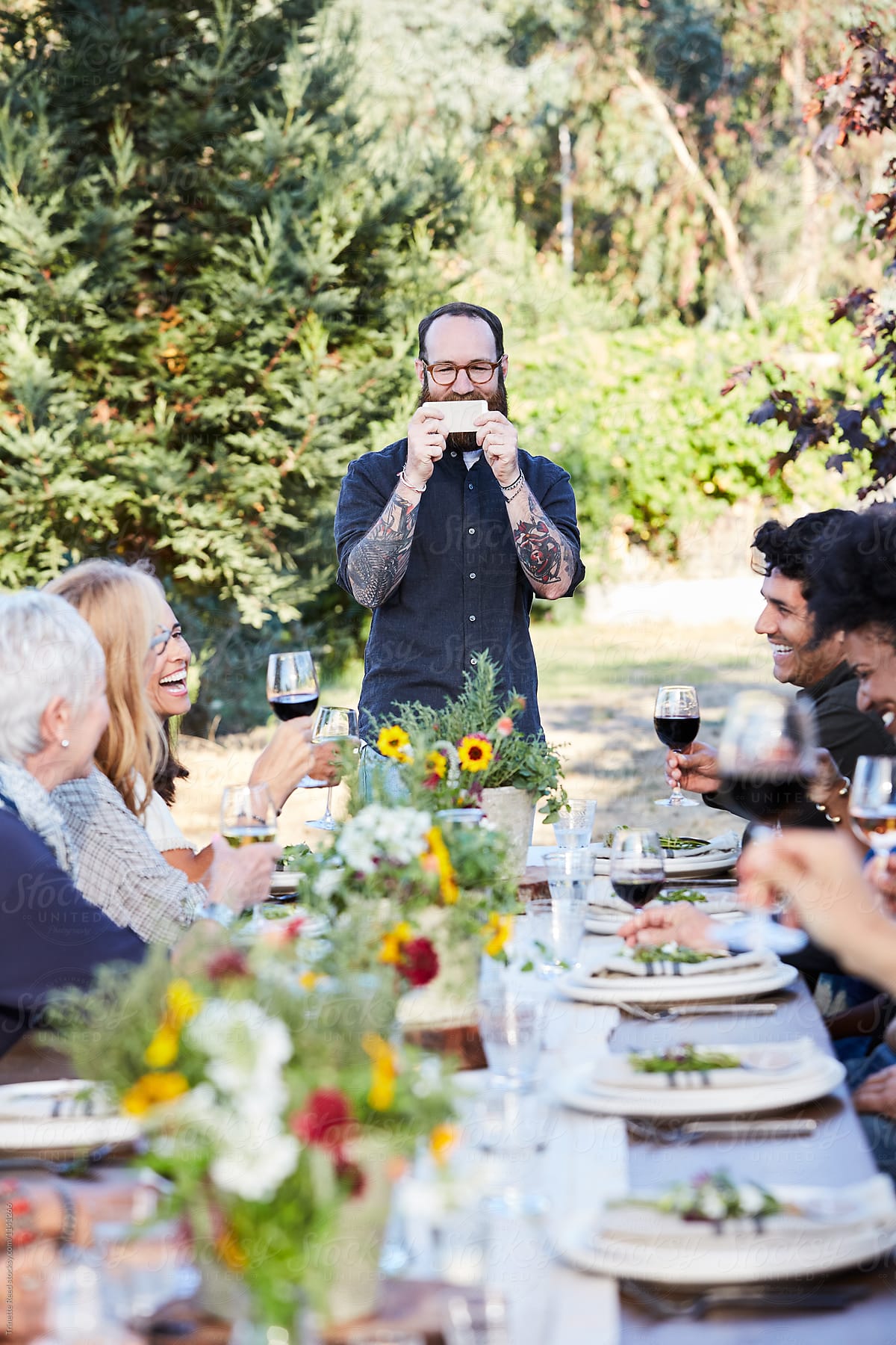 Man taking a photo at outdoor dinner party of friends